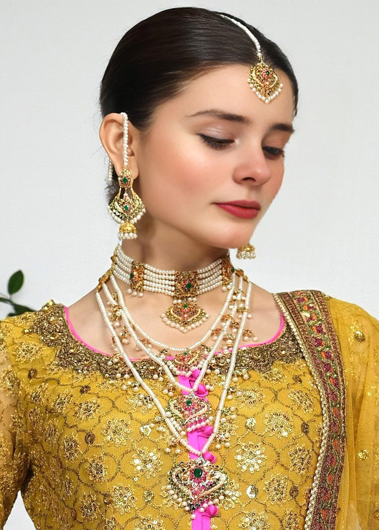 Woman wearing traditional jewelry and a yellow outfit with intricate designs.