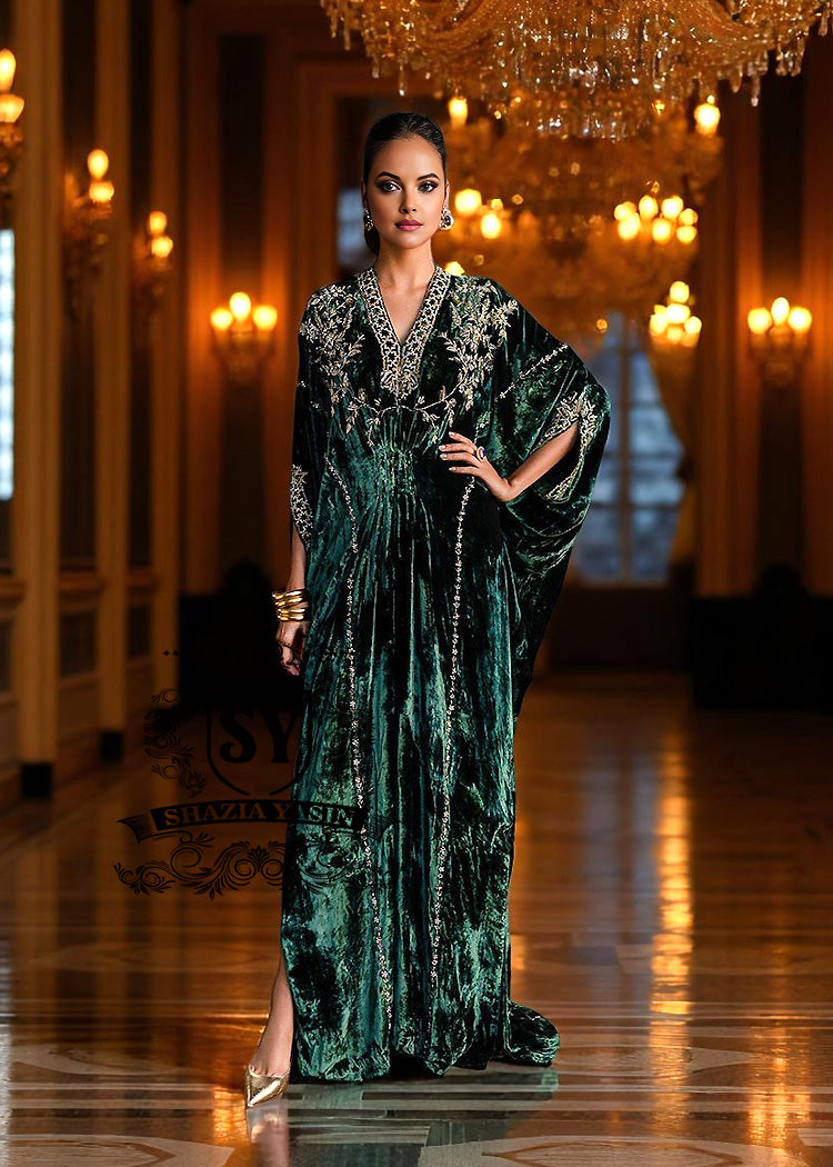 Woman in an elegant green Kaftan dress standing in a luxurious hallway with chandeliers.