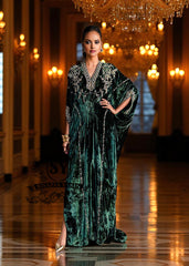 Woman in an elegant green Kaftan dress standing in a luxurious hallway with chandeliers.