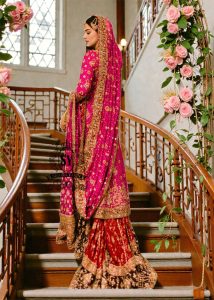 A timeless bridal dress design that exudes classic elegance and meticulous craftsmanship. The intricately crafted, opulent Banarsi Jamawar lehenga exudes a royal flair, with its heavy maroon and red borders creating a magnificent, flowing train.