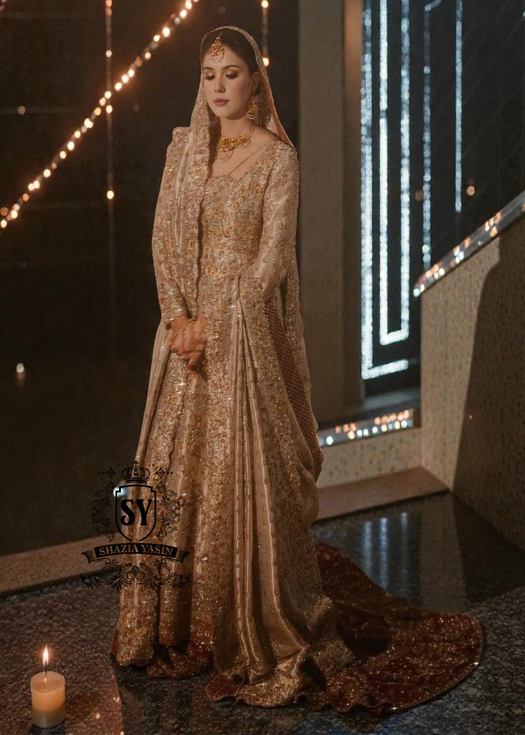 BridalDress199A A vision of divine luminosity, this pishwas glimmers like starlight with every movement. Her Lehenga features intricate gold embroidery, delicate florals and crystal embellishments, while her lame dupatta envelops her like a dream.