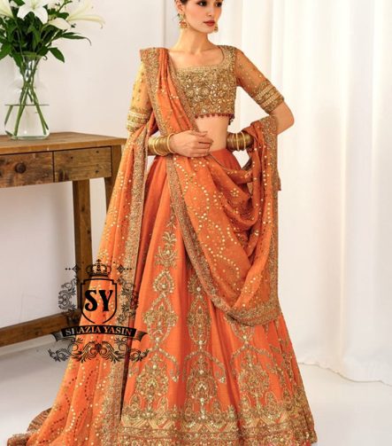 A stunning ensemble featuring Persimmon net blouse and an intricately embroidered Raw silk lehenga in the same vibrant hue. A shimmering kaamdani dupatta adds charm and sophistication to the ensemble.