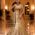 Ivy is a mermaid wedding dress that fascinates with the refinement of its lehenga silhouette, which delicately follows the lines of the body and highlights a timeless elegance. The blouse of the dress is outlined by a embellished neckline, while the long sleeves, made entirely of net with shiny floral embellishments, add an extra touch of sophistication.