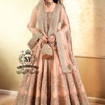 In a radiant shade of Peach puff, this bridal dress captures a timeless grandeur, sweetened with touches of pastel romance. This open-cut kalidaar gown shines with tissue silk lehenga.