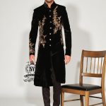 The Rich Black Sherwani jacket with a mandarin collar and jeweled shimmering gold zari embellishments on the front evokes regal elegance, reinterpreted with a modern twist.