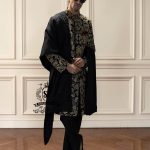 This luxurious royal black velvet sherwani, adorned with opulent gold hand embroidery, exudes a bold and dignified presence. The plush velvet fabric highlights the depth of the intricate hand embellishments, creating a truly regal style befitting a groom or a grand ceremony.