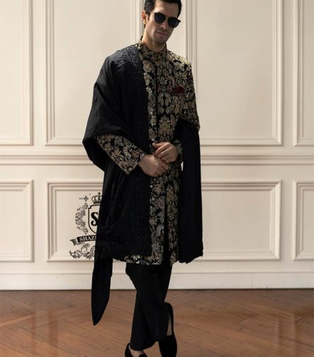 This luxurious royal black velvet sherwani, adorned with opulent gold hand embroidery, exudes a bold and dignified presence. The plush velvet fabric highlights the depth of the intricate hand embellishments, creating a truly regal style befitting a groom or a grand ceremony.