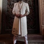 The Luminescence Ivory White Sherwani is a vision of refined romance, crafted in luminous karandi silk that seems to glow with elegance—hand embellishments on the collar and sleeves whispers of heritage artistry,