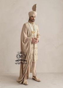 This sherwani is a masterpiece that blends timeless nobility with a modern sensibility. A finely hand-embroidered sherwani by Shazia Yasin, elevated with gold accents, paired with a statement mala, shawl and a bold turban for a timeless yet striking look.