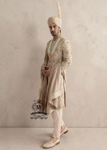 This sherwani is a masterpiece that blends timeless nobility with a modern sensibility. A finely hand-embroidered sherwani by Shazia Yasin, elevated with gold accents, paired with a statement mala, shawl and a bold turban for a timeless yet striking look.