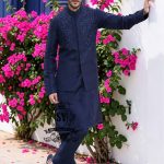 A stylish waistcoat crafted from luxurious navy blue raw silk fabric. The waistcoat itself, the front, and the sleeves are adorned with intricate threadwork and embroidery, giving it a refined and traditional feel.